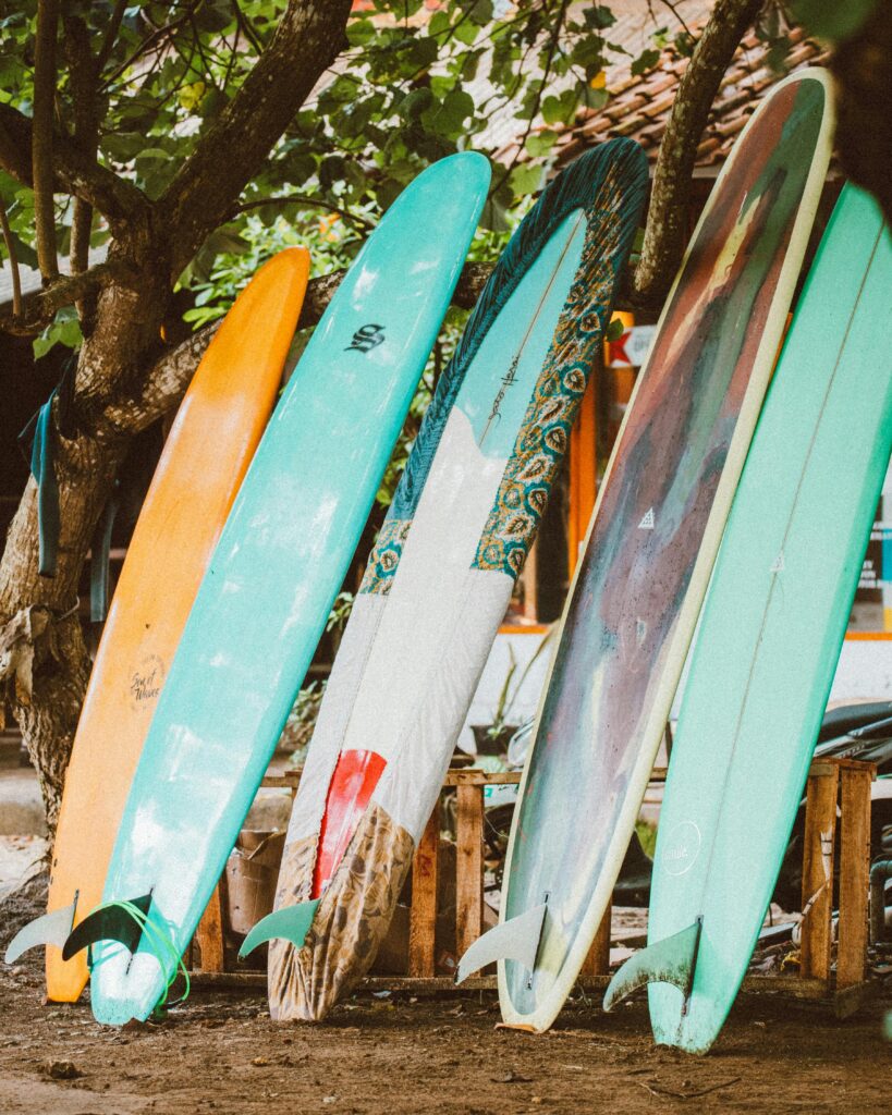 pexels-photo-4318971-4318971 Vibrant surfboards lined up under a tree, perfect for beach and surf themes.